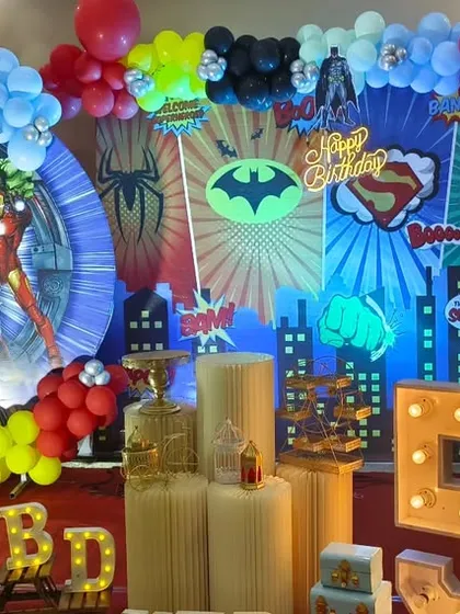 For the ultimate superhero fan, I created this action-packed Avengers birthday party stage. The setup features a dynamic city skyline backdrop, multiple superhero cutouts including the Hulk and Iron Man, themed balloon arrangements, and a large light-up number '5'.