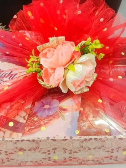 A beautifully wrapped Rakhi hamper tray in red, filled with dry fruits and other goodies.