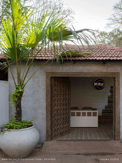 The entrance to Sanctuary Bar & Kitchen, featured in The Architect's Diary. The image shows the rustic carved wooden door and a simple potted palm, setting a tone of understated, natural elegance.