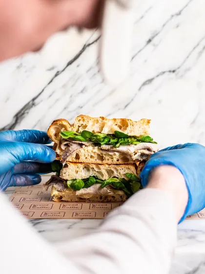 A candid shot of a chef styling a sandwich between takes. This shows the attention to detail that goes into making every menu item look its absolute best.