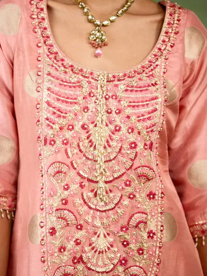 A close-up of the exquisite hand-embroidery on the pink sharara kurta. The combination of zardozi and threadwork in shades of pink and gold highlights the artisanal finesse of the piece.