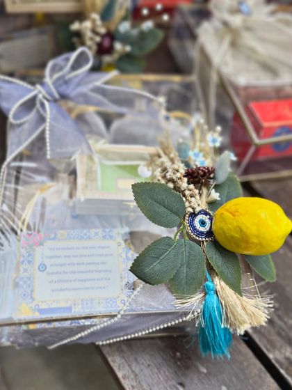 This hamper features a personalized card explaining the meaning of the evil eye charm. The blue tassel and lemon motif tie back to the overall Moroccan theme, creating a thoughtful and well-rounded gift.