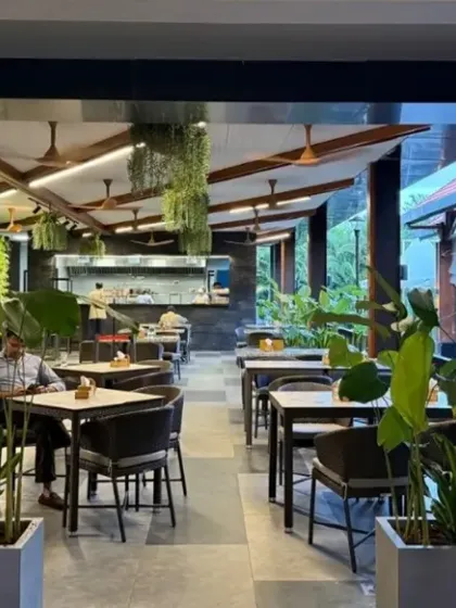 An evening view of the KGA cafe, where the landscape design is enhanced by strategic lighting. The planters and hanging ferns create soft shadows and a warm, inviting atmosphere for members and guests.
