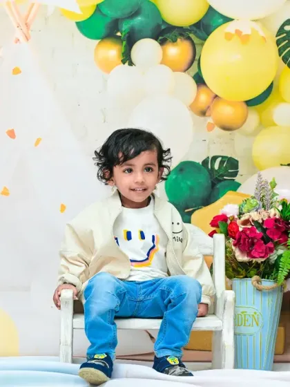A candid shot of the toddler during his second birthday photoshoot, looking curious and happy. The natural light and festive decor create a warm and inviting portrait.