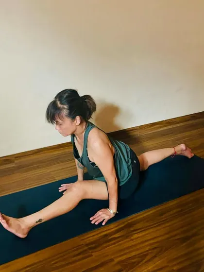 A student works on her Hanumanasana (splits) in a group class. The community atmosphere is encouraging and non-competitive.
