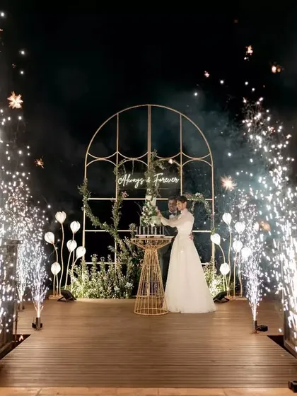 A truly magical moment. We framed the couple's reception with a custom arch and sparklers against the backdrop of a serene lake, creating an unforgettable 'Always & Forever' memory.