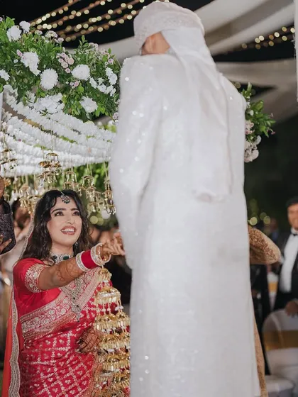 The bride's happy glance at her groom as she walks down the aisle under a stunning phoolon ki chadar. This is the moment where her forever begins.