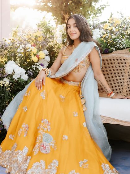 A full-length view of the sun-kissed floral Mehendi look. The bright yellow lehenga is perfectly complemented by the fresh, dewy makeup.