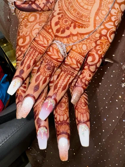 An elegant choice for a bride. These long, square-shaped extensions have a soft white and nude ombré base with a touch of glitter and delicate crystal placements near the cuticle.