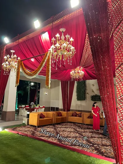 A beautifully arranged lounge area under a red canopy, showing how we use lighting and draping to create intimate spaces within a large venue.