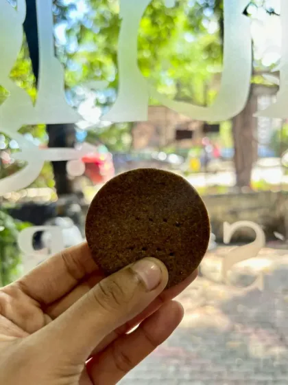 Holding up one of our millet jaggery cookies to the light. It's a simple, honest cookie that I'm very proud of. The deep color comes from the combination of millet and jaggery.