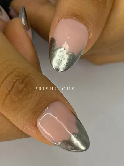 A close-up of these oval-shaped press-on nails with a melted silver chrome tip design. This is such a cool and edgy take on a French manicure.