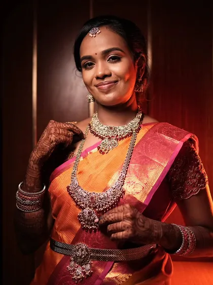 A beautiful reception look with a bright orange and pink saree, paired with stunning silver jewelry.