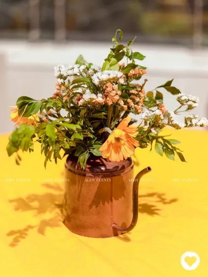 A rustic watering can used as a vase for a floral centerpiece, adding a unique and charming touch to the table decor.