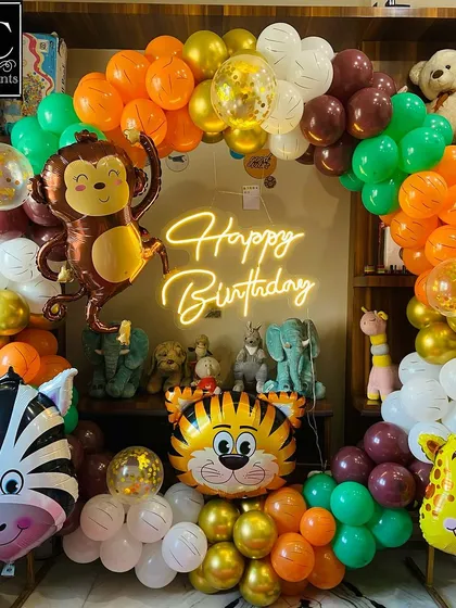 This jungle-themed birthday decoration brings the safari indoors. A lively balloon arch in orange, green, and gold frames a collection of animal friends, including a monkey, zebra, and tiger, perfect for a fun-filled celebration.