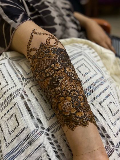 A close-up of a dense, full-arm design. This style combines bold Arabic florals with the fine, detailed filler work of Indian mehendi.