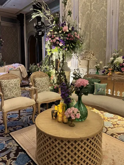 An elegant lounge area with vintage furniture, tall floral arrangements, and carefully chosen cushions, demonstrating a keen eye for sophisticated styling.