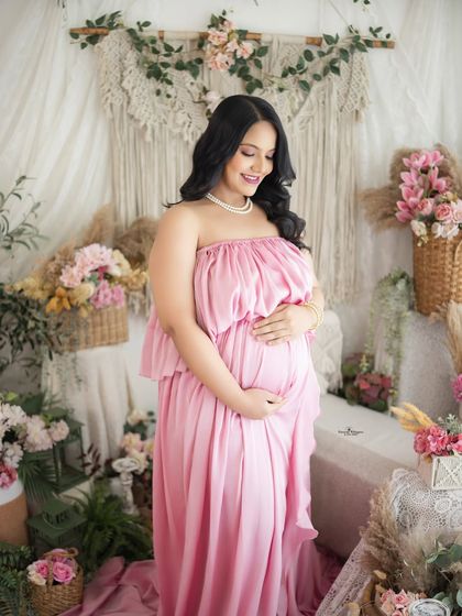 A smiling and happy solo portrait. The mother-to-be cradles her bump, looking down with a gentle smile, perfectly capturing the joy of anticipation.