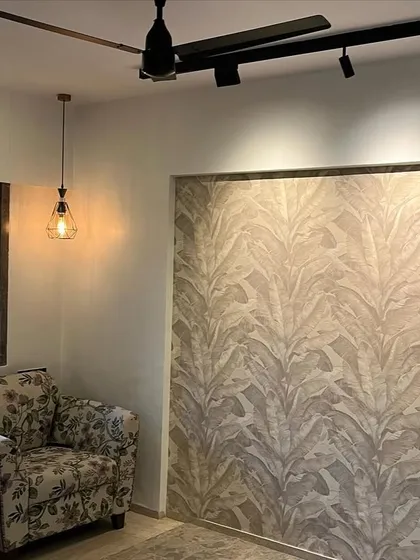 A closer look at the accent wall and seating nook, showcasing the texture of the wallpaper and the simple comfort of the floral armchair.