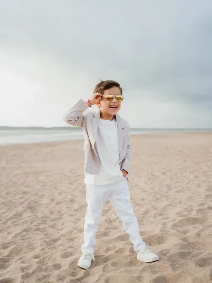 The birthday boy looking cool and confident in a stylish suit and sunglasses on the beach. A fun solo portrait from his 5th birthday celebration.