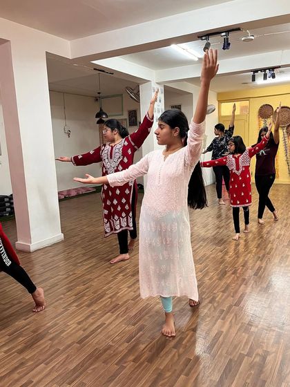 Students in my semi classical weekend session, practicing a pose that requires balance and grace. Their arms are raised in a beautiful, expressive gesture.