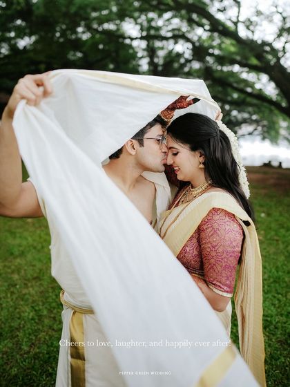 A tender kiss under a traditional mundu, a classic and romantic shot from Anjana and Avirup's Kerala wedding.