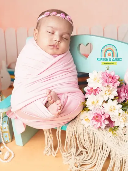 A stylish 2-month-old baby girl in a "little fashionista" setup, complete with a miniature handbag, makeup palette, and pearls.