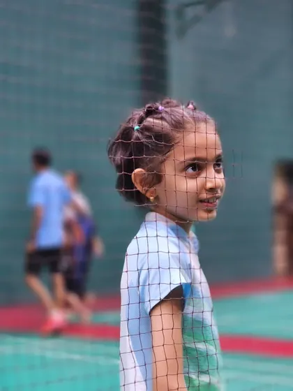 A young player watches the game with bright eyes, dreaming of her own future on the court.