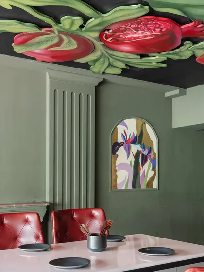 The finished restaurant interior, where the ceiling mural with its ripe pomegranates complements the arched floral paintings on the wall. The entire space is unified by a cohesive artistic vision.