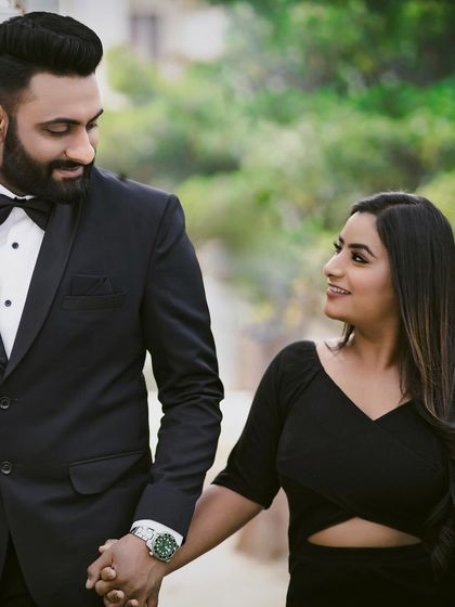 A stylish pre-wedding look with the couple in coordinated black outfits. Her makeup is chic and modern, with a focus on flawless skin and a defined lip.
