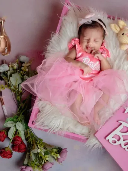 A doll in her own little world. This Barbie-themed shoot is filled with fun props like miniature perfume bottles and makeup, creating a glamorous and adorable portrait.