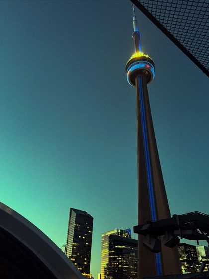 A dramatic low-angle shot of Toronto's CN Tower at night, taken from a concert. This captures an iconic Toronto experience.
