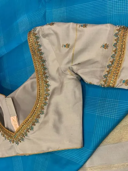 A close-up of the grey silk blouse, highlighting the subtle embroidery that complements the blue and grey saree.