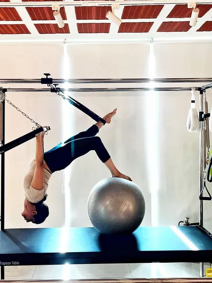 The Pilates journey is a lifestyle change. This inverted pose using the stability ball on the Cadillac is a testament to the transformation that is possible with commitment.