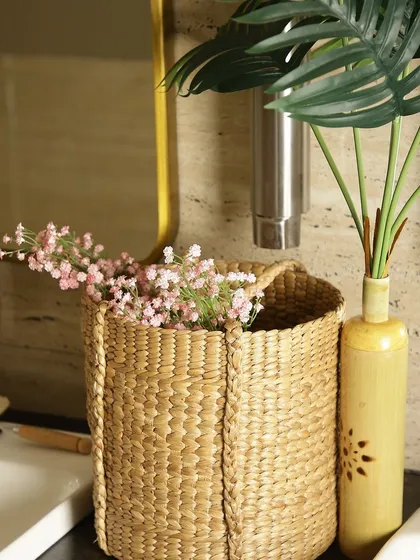 A woven seagrass basket used as a decorative holder in a bathroom setting. It elegantly contains a small bouquet of flowers, showing how our baskets can add a touch of natural beauty to any space.