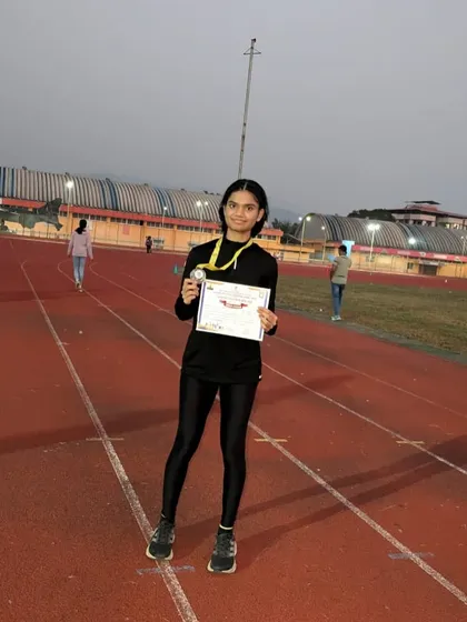 An athlete proudly displays her bronze medal won in the 100m hurdles at the state championships in Chiplun.