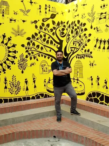 Here I am with a completed Warli painting, a traditional Indian folk art style. This large-scale mural brings immense energy and cultural richness to the space. I love working on such intricate designs that celebrate our heritage.