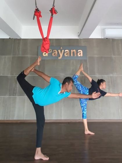 A teacher and student practice Natarajasana together, showcasing the partnership and support in our community.