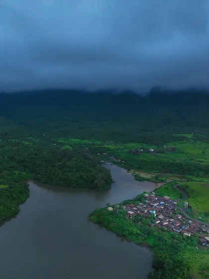 The village of Kondeshwar under dark monsoon clouds. The mood is dramatic and beautiful, showcasing the power of the approaching rain.