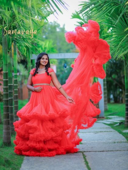 Capturing movement and joy, this shot shows the red gown's trail flowing in the air as the mother-to-be walks down a garden path.