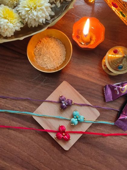 These beautiful floral rakhis are made from fabric beads and come in purple, teal, and red. Each one is carefully crafted by hand.