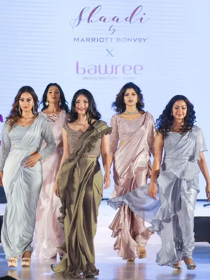 A group of models walking the ramp in a collection of elegant, modern sarees in pastel and metallic shades.