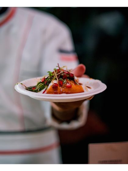A chef holds a plate of our Indian fusion creation, beautifully garnished with microgreens and pomegranate seeds. The vibrant colours and artistic plating demonstrate our commitment to making food that is as beautiful as it is delicious.