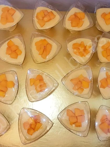 A batch of my Mango Souffle Shots, ready for a party. These triangular cups are filled with creamy mango souffle and topped with fresh fruit.
