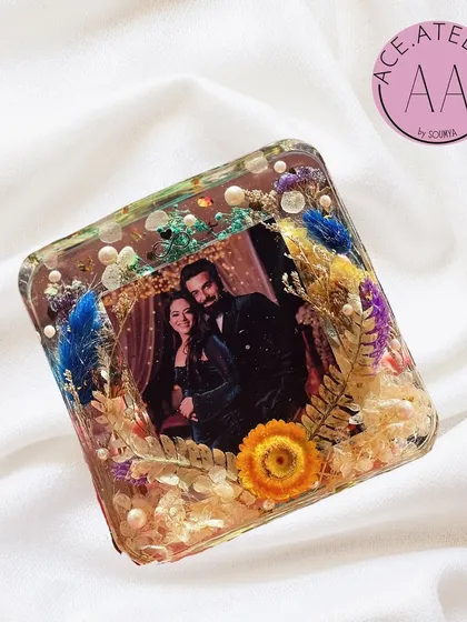 A square resin photo block preserving a couple's picture with colorful flowers and gold foil. It's a compact and beautiful way to display a favorite memory.