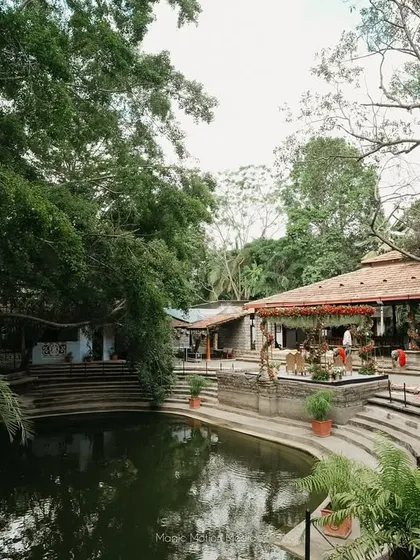 A wide view of a wedding setup by the pond, capturing the entire ambiance of a large-scale celebration.