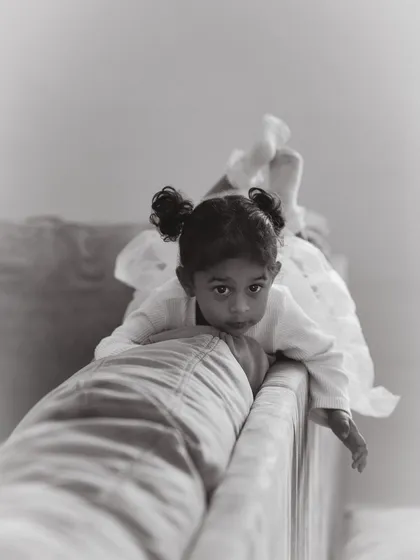 Sometimes the quietest moments are the most powerful. This is a gentle portrait of a young girl peering over the couch, a candid moment of curiosity captured during an in-home family session.