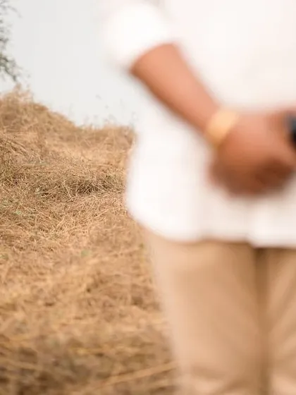 An artistic composition focusing on the bride-to-be standing in a field of dry grass, with her partner blurred in the foreground. This creative shot evokes a sense of anticipation and connection.