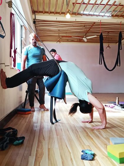 Using a yoga chair and wall ropes, this student is able to explore a supported backbend that would be difficult to achieve otherwise.