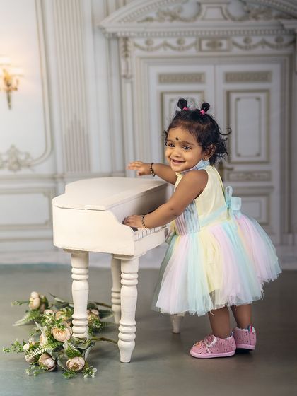 Her laughter is the sweetest song in the room. Dressed in a rainbow tutu, this little musician is ready for her piano debut.